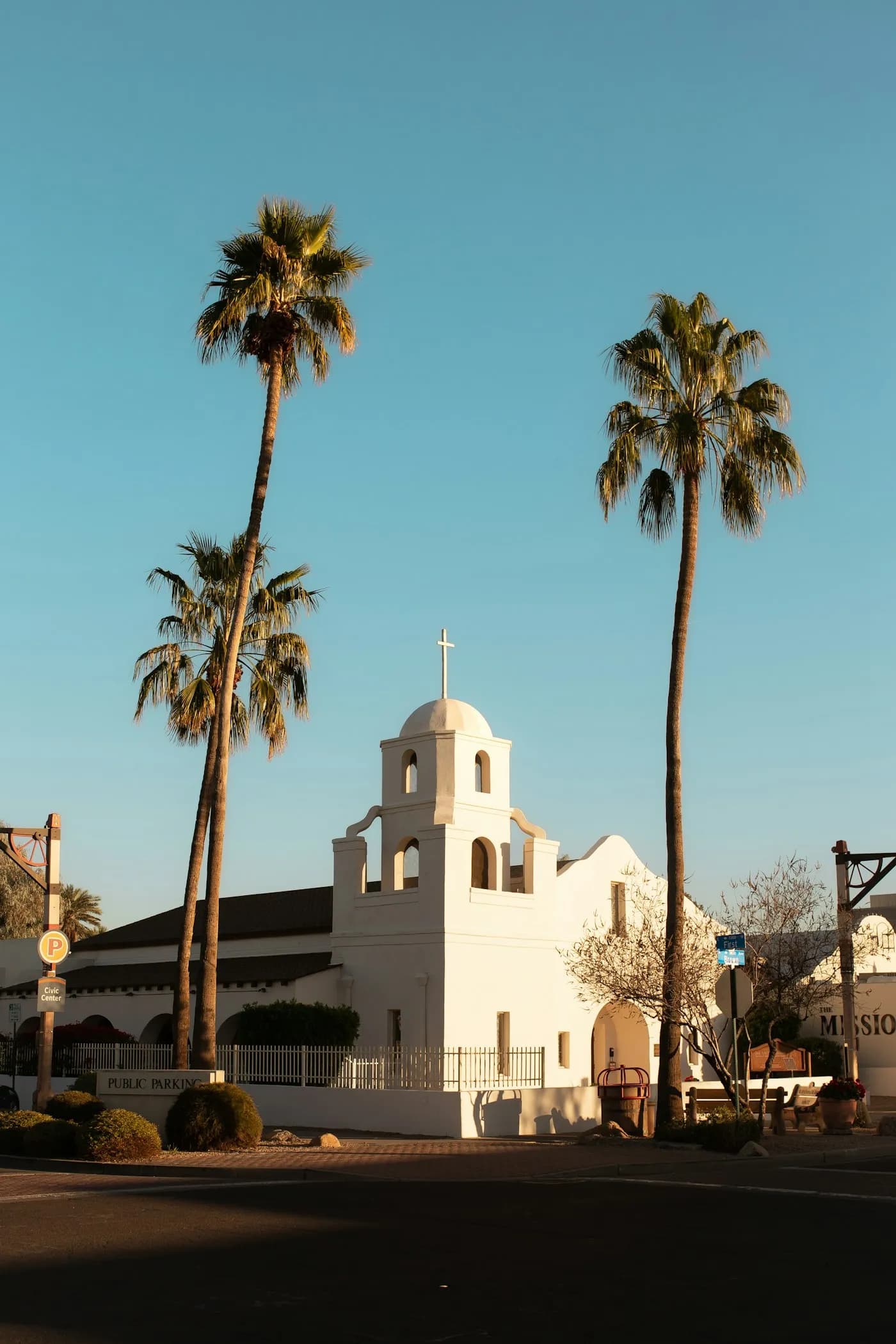 The white Old Adobe Mission in Scottsdale, framed by palm trees and blue sky
