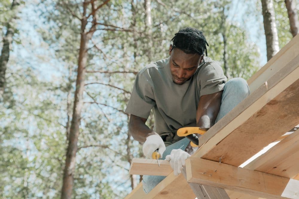 A carpenter carefully sawing timber during an outdoor home project